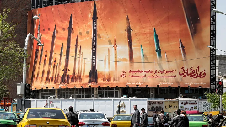 Motorists drive past a billboard depicting named Iranian ballistic missiles in service